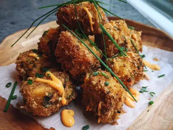 crispy protein nuggets coated in golden glaze, served in a white ceramic dish with fresh herbs sprinkled on top