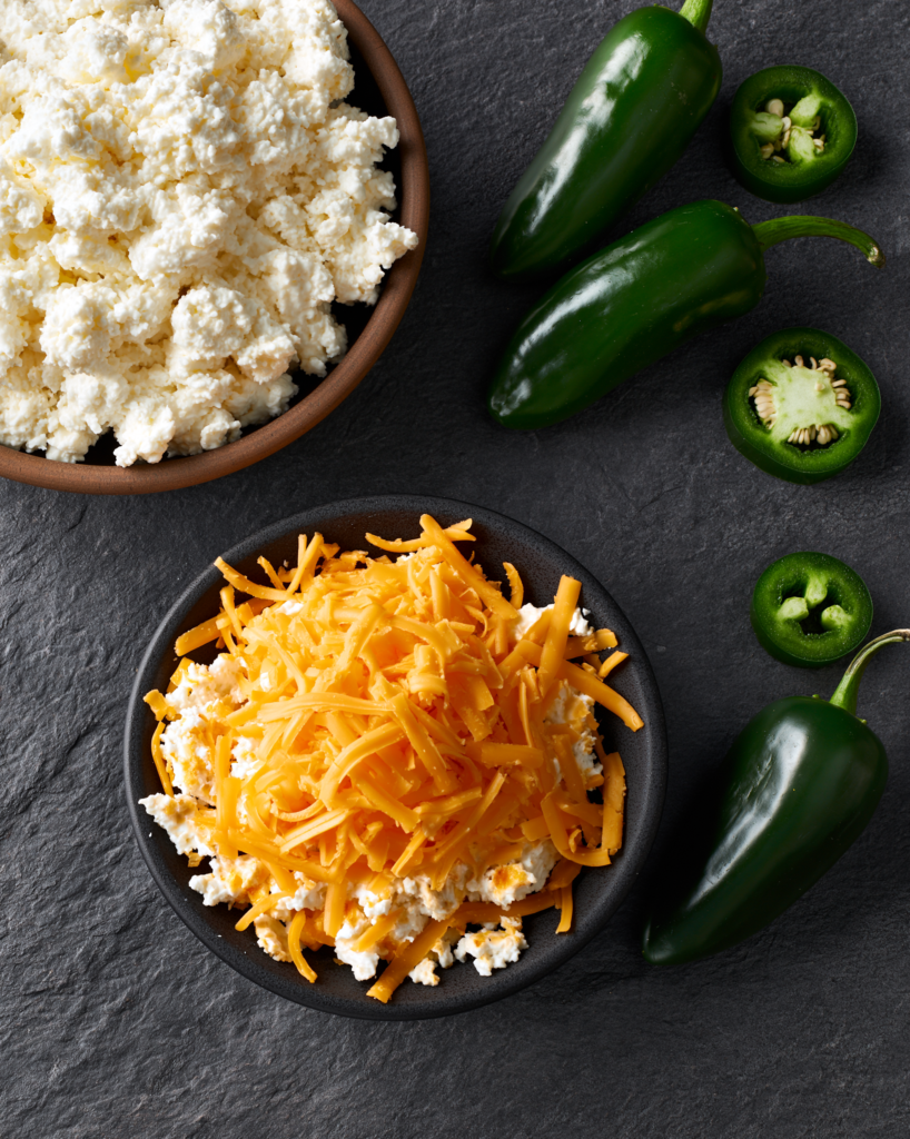 Flat lay of jalapeño cheddar cottage cheese chips ingredients: cottage cheese, shredded cheddar, fresh jalapeños